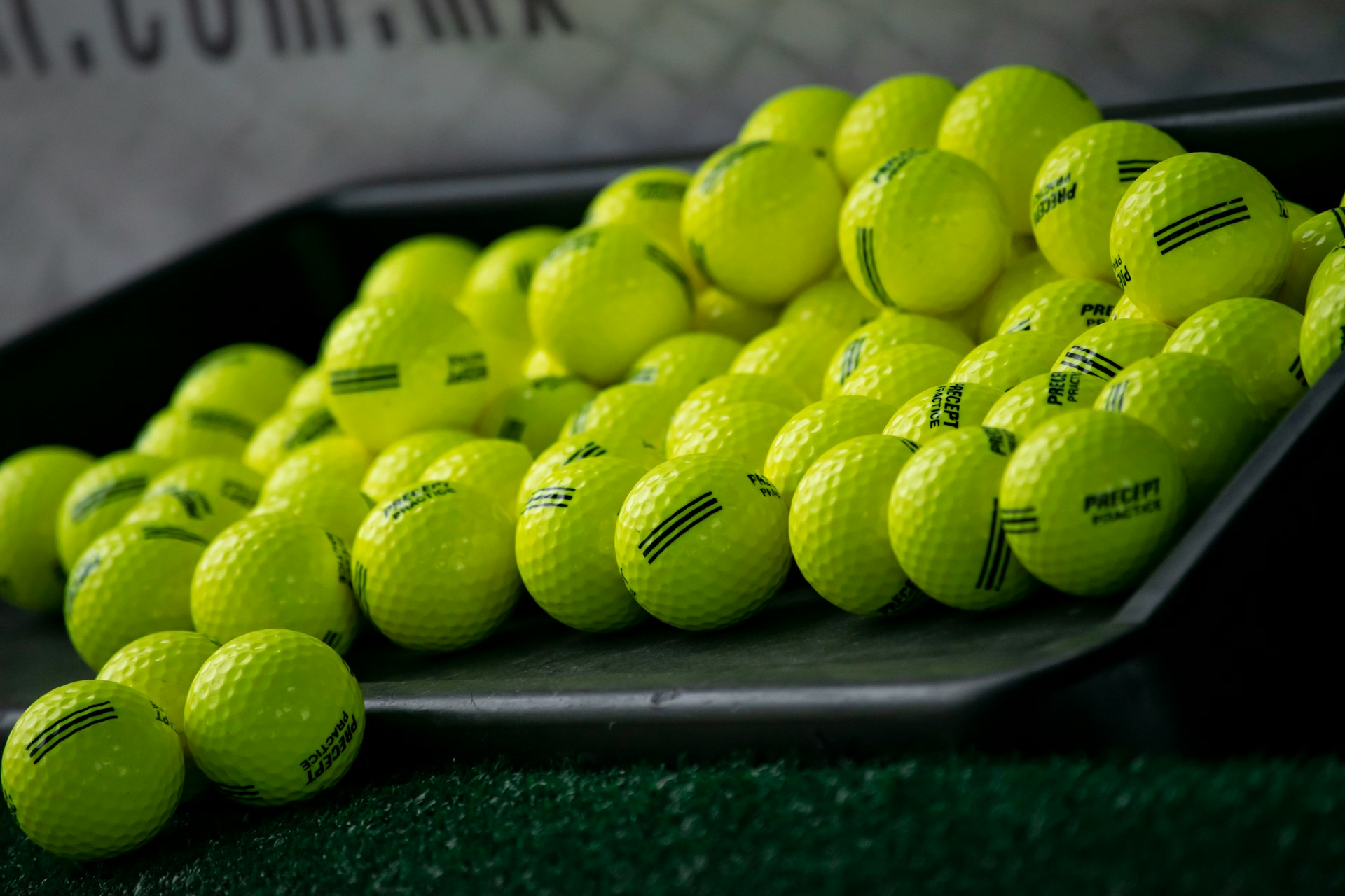 Yellow practice golf balls in a tray on a simulator hitting mat