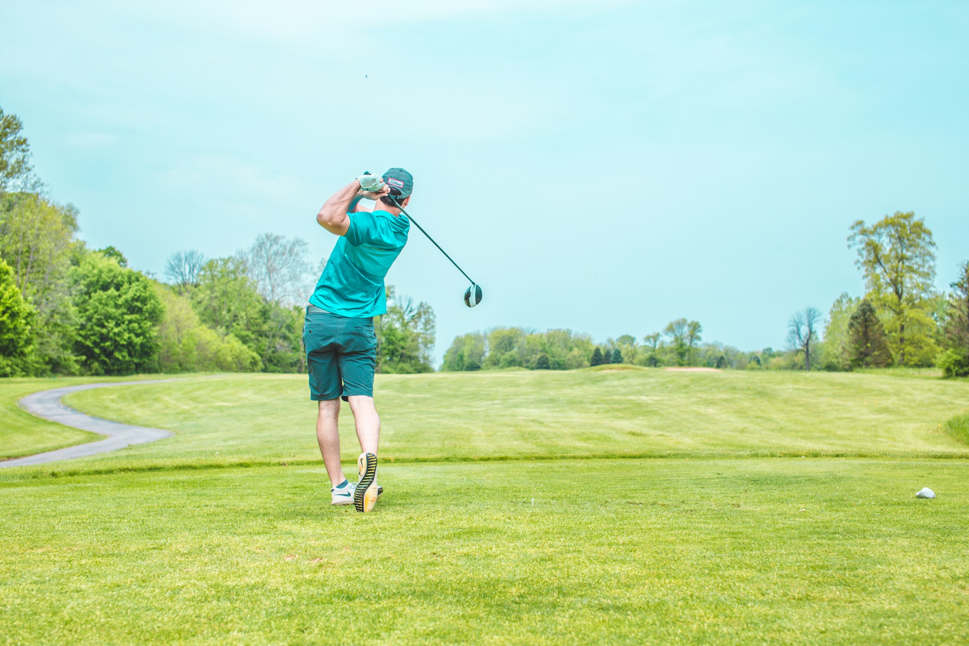 Golfer completing a driver swing on a golf course fairway